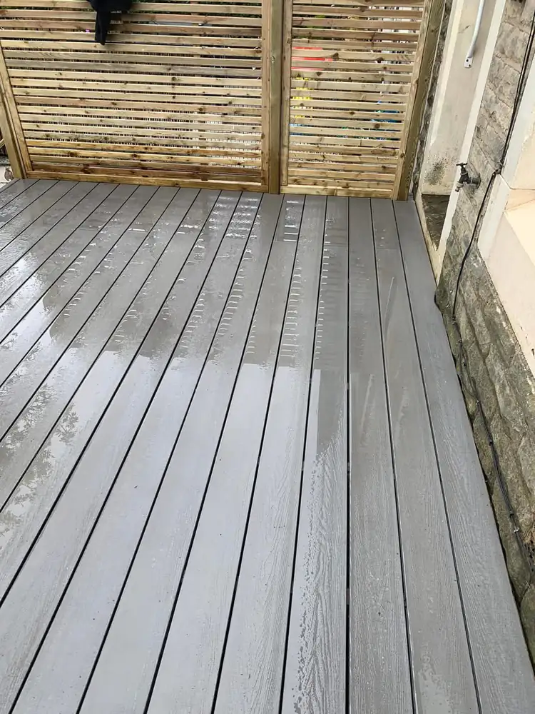 Gray composite decking with wet wood slat fence